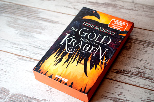 Das Gold der Krähen, Buch liegend auf weißem Holzbrett