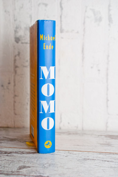 Momo, aufrecht stehend fotografiert; man sieht den Buchrücken