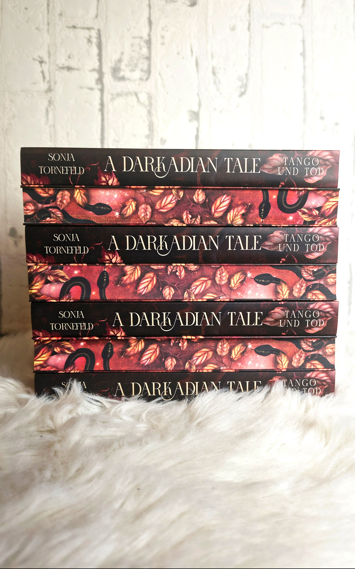 Buchstapel, der abwechselnd den Farbschnitt und den Buchrücken des Buches "A Darkadian Tale - Tango und Tod" zeigt
