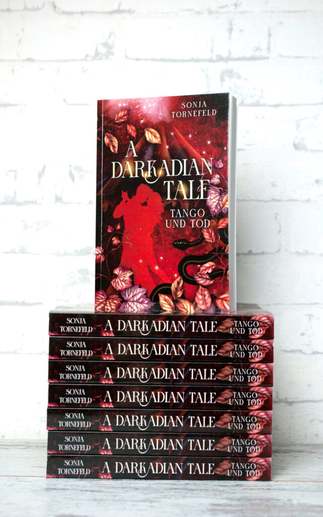 A Darkadian Tale Tango und Tod. Buch stehend auf Buchstapel vor weißem Hintergrund