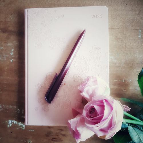Blogtitelbild zeigt ein Notizbuch, Stift und Rose von oben fotografiert; Schmuckbild