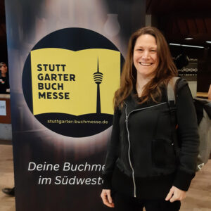 Fantasyautorin Sonja Tornefeld steht vor einem Roll-Up der Stuttgarter Buchmesse. Titelbild Blogbeitrag.
